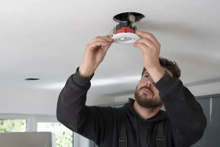 Close-up of an electrician fitting a recessed downlight into a ceiling